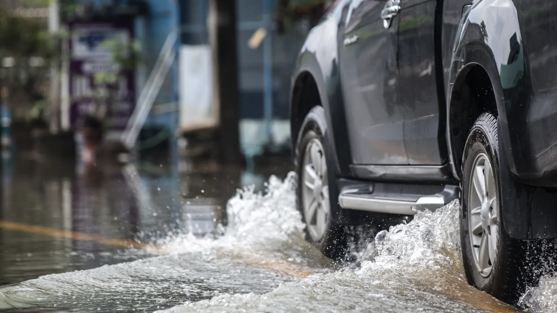 Auto transitando por calle mojada con riesgo de aquaplaning en lluvia